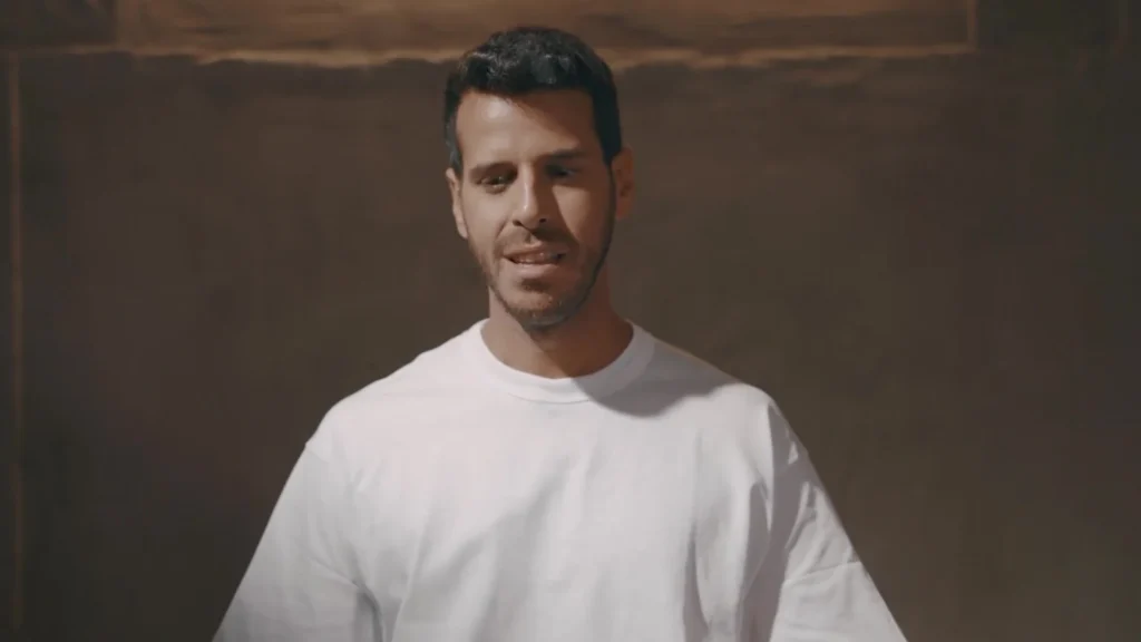 שחקן בחולצה לבנה מול רקע חום מתוך פרומו פרס ספיר 2023