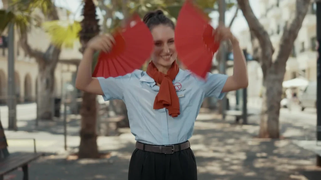 מגישת הקמפיין עם צעיף אדום ושתי מניפות בתחנת הרכבת הקלה