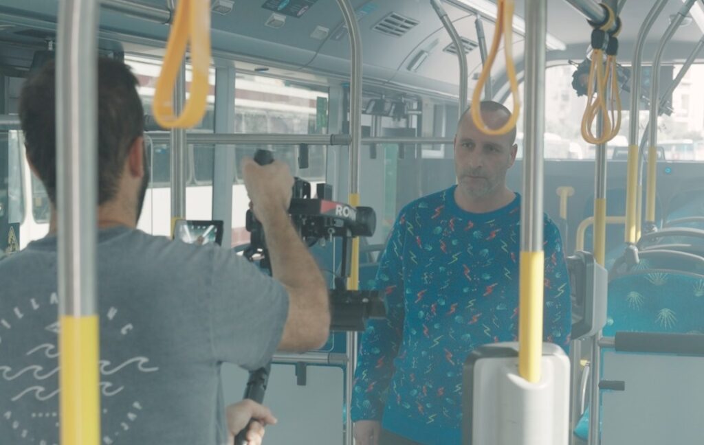 צלם מצלם נהג אגד לבוש בסוודר בתוך אוטובוס